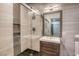 Modern bathroom with neutral tile, glass enclosed shower, wooden vanity and contemporary fixtures at 1793 Clear River Falls Ln, Henderson, NV 89012