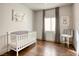 This bedroom features hardwood floors, a window, artwork, a crib, and a chair at 1793 Clear River Falls Ln, Henderson, NV 89012