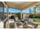 Relaxing covered patio with wicker furniture, barbecue, and view of the landscaped backyard and lawn at 1793 Clear River Falls Ln, Henderson, NV 89012