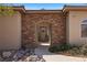 Charming home entrance with a stone archway, rustic wood door, and well-kept landscaping at 1981 Trophy Elk Ave, Logandale, NV 89021