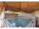 Private hot tub is enclosed in a tiki hut with a thatched roof and white curtains at 603 Fiddlehead Ave, Las Vegas, NV 89183
