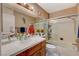 Bathroom featuring a shower-over-tub with a glass enclosure, wooden vanity, and a decorative bird at 611 Spyglass Ln, Las Vegas, NV 89107