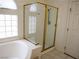 Bright bathroom featuring a glass shower with gold trim and a large soaking tub under a window at 6508 Alpine Forest Ct, Las Vegas, NV 89149