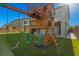 Backyard play area features a wooden playhouse, swings, and artificial turf for a fun and safe outdoor experience at 7364 Marbury St, Las Vegas, NV 89166