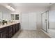 Bathroom featuring dark wood cabinets, dual sinks, and a glass-enclosed shower and tub at 7364 Marbury St, Las Vegas, NV 89166