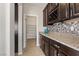 Butler's pantry with dark wood cabinets, granite countertops, wine rack, and access to the walk-in pantry at 7364 Marbury St, Las Vegas, NV 89166