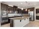 Well-equipped kitchen with dark wood cabinets, granite countertops, stainless steel appliances, and a large island at 7364 Marbury St, Las Vegas, NV 89166