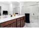Bathroom featuring a double vanity with dark wood cabinets and a glass-door shower-tub at 10352 Rye Patch Creek St, Las Vegas, NV 89141