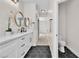 Modern bathroom with black hexagon tile floors, marble countertop and dual mirrors, leading to an adjacent toilet room at 10613 Turquoise Valley Dr, Las Vegas, NV 89144