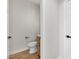 A modern powder room with a wood vanity, white toilet, and neutral wall color at 10613 Turquoise Valley Dr, Las Vegas, NV 89144