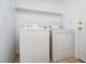 Convenient laundry area with white washer and dryer, shelving, and tiled flooring at 110 Wynntry Dr, Henderson, NV 89074