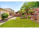 Expansive backyard with artificial turf, brick patio, tiered retaining wall, and mature landscaping at 11764 Golden Moments Ave, Las Vegas, NV 89138