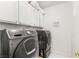 Modern laundry room featuring front-load washer and dryer with upper cabinet storage at 11764 Golden Moments Ave, Las Vegas, NV 89138