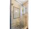 Luxurious shower with glass door, decorative tile accent wall, mosaic stone floor, and convenient shelving at 11764 Golden Moments Ave, Las Vegas, NV 89138