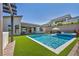 Inviting backyard boasts a pool, integrated spa, modern lounge chairs, and lush artificial grass at 11954 Camden Ridge Ct, Las Vegas, NV 89138