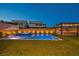 Backyard featuring a sparkling pool, outdoor kitchen, and lush artificial turf illuminated at twilight at 11954 Camden Ridge Ct, Las Vegas, NV 89138