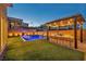 Backyard at dusk featuring a pool, in-water loungers, outdoor kitchen, and professionally landscaped yard at 11954 Camden Ridge Ct, Las Vegas, NV 89138