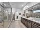 A luxurious bathroom with double sinks, stone accent wall, and a glass-enclosed shower at 11954 Camden Ridge Ct, Las Vegas, NV 89138