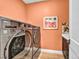 Well-equipped laundry room features modern machines, a utility sink, and stylish peach-painted walls at 11954 Camden Ridge Ct, Las Vegas, NV 89138