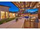 Evening view of outdoor kitchen, featuring a grill, bar seating, and a pergola with ambient lighting at 11954 Camden Ridge Ct, Las Vegas, NV 89138