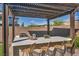 Outdoor kitchen with marble countertops, built-in grill, and seating under a pergola at 11954 Camden Ridge Ct, Las Vegas, NV 89138