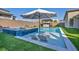 Backyard swimming pool with tanning ledge, sun loungers, and outdoor kitchen under a striped umbrella at 11954 Camden Ridge Ct, Las Vegas, NV 89138