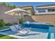 Relaxing shallow tanning ledge with lounge chairs and umbrella providing the ultimate backyard oasis at 11954 Camden Ridge Ct, Las Vegas, NV 89138