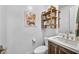 Stylish powder room featuring vanity with bronze fixtures, floating wood shelves, and fun artwork at 11954 Camden Ridge Ct, Las Vegas, NV 89138