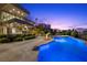 A large, illuminated pool with a waterfall feature and lush landscaping at 1472 Macdonald Ranch Dr, Henderson, NV 89012
