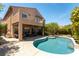 Home exterior featuring a refreshing backyard pool, covered patio, lush landscaping, and upper-level balcony at 2434 Amoretti St, Henderson, NV 89052