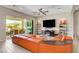 Modern living room with an orange leather sectional sofa and access to outdoor patio with dining set at 2579 Speyburn Ave, Henderson, NV 89044