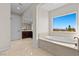Bright bathroom with marble tile flooring, large soaking tub and dark wood vanity at 2717 Mona Lisa St, Henderson, NV 89044