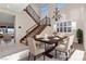 Elegant dining room with a wooden table set for six, iron chandelier, and staircase, great for Gathering dinners and gatherings at 2717 Mona Lisa St, Henderson, NV 89044