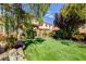 A manicured backyard with lush green lawn, mature trees, and serene seating area at 4017 Kristina Lynn Ave, North Las Vegas, NV 89081