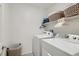 Bright laundry room features a washer, dryer, and ample storage with baskets on the upper shelf at 489 Filaree Pl, Henderson, NV 89015