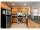Functional kitchen featuring stainless steel appliances, granite counters, wooden cabinetry and tile flooring at 6623 Brick House Ave, Las Vegas, NV 89122