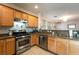 Functional kitchen featuring stainless steel appliances, granite counters, wooden cabinetry and tile flooring at 6623 Brick House Ave, Las Vegas, NV 89122