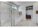 Modern bathroom featuring a glass-enclosed shower, soaking tub, and light wood-look flooring at 6830 Compass St, North Las Vegas, NV 89084