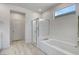 Bathroom featuring a glass-enclosed shower, soaking tub, and light wood-look flooring at 6830 Compass St, North Las Vegas, NV 89084