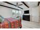 Bedroom with dark ceiling beams, a ceiling fan, and large windows allowing natural light at 6830 Compass St, North Las Vegas, NV 89084