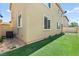 Artificial turf backyard with an air conditioning unit along the home's exterior at 7189 Ashcroft St, North Las Vegas, NV 89084