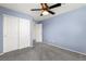 Carpeted bedroom with double closet, ceiling fan, and neutral-colored walls at 7189 Ashcroft St, North Las Vegas, NV 89084