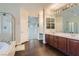 Bright bathroom featuring dual sinks, a walk-in shower, and wood-look flooring at 7337 Savannah Falls St, Las Vegas, NV 89131