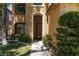 Inviting front entrance with arched doorway, lush landscaping, and sidewalk access at 7736 Villa Andrade Ave, Las Vegas, NV 89131