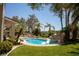 A backyard pool has rock features, a slide, tropical landscaping and green grass with a patio and seating areas at 9905 Fox Springs Dr, Las Vegas, NV 89117