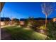 Serene backyard at dusk with garden lights, retaining wall, and a lush green lawn at 16 Cresta Villa Ct, Henderson, NV 89011