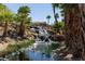 Relaxing backyard waterfall and stream with lush greenery and mature palm trees at 16 Cresta Villa Ct, Henderson, NV 89011