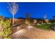 Beautiful backyard with tiered garden beds, ambient lighting, a retaining wall, and a lush lawn at 16 Cresta Villa Ct, Henderson, NV 89011