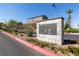 A stone monument sign welcomes residents to Alta Fiore, with landscaping, trees, and a glimpse of homes in the background at 16 Cresta Villa Ct, Henderson, NV 89011