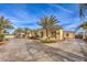 An exterior view of the home with a large circular driveway, mature landscaping and desert vegetation at 2780 El Camino Rd, Las Vegas, NV 89146